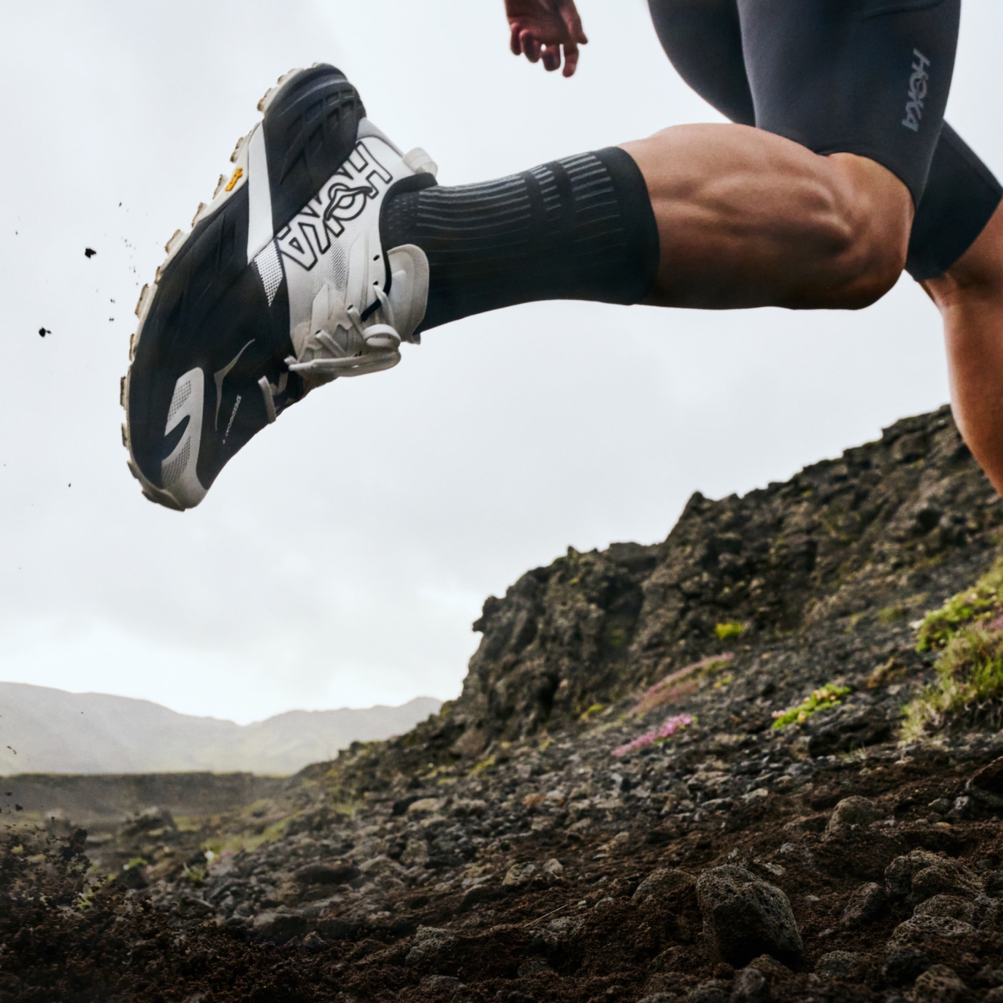 A person runs through rocky terrain in their HOKA Speedgoat 7 shoes.