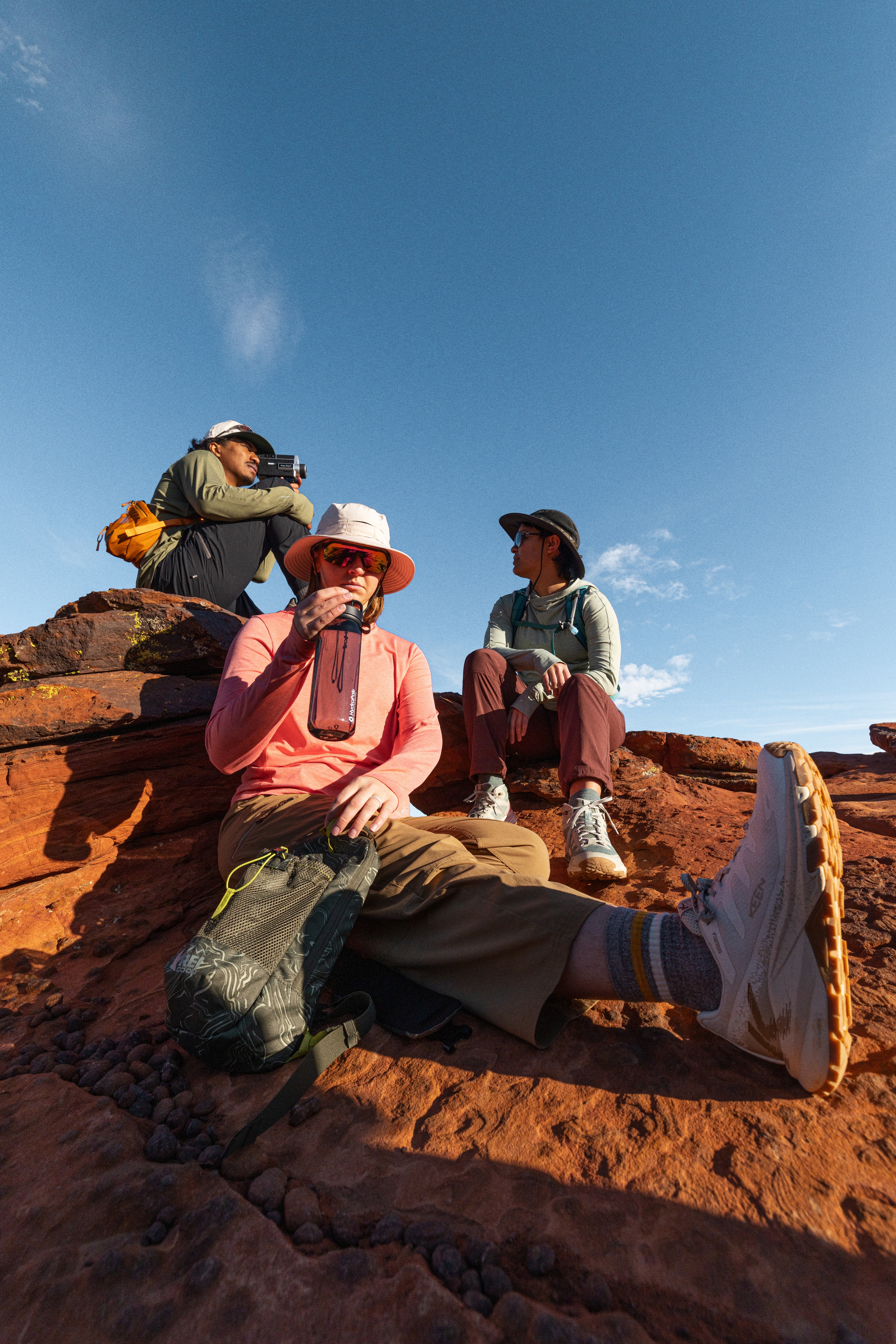 Three hikers pause for a break on a sunny day.
