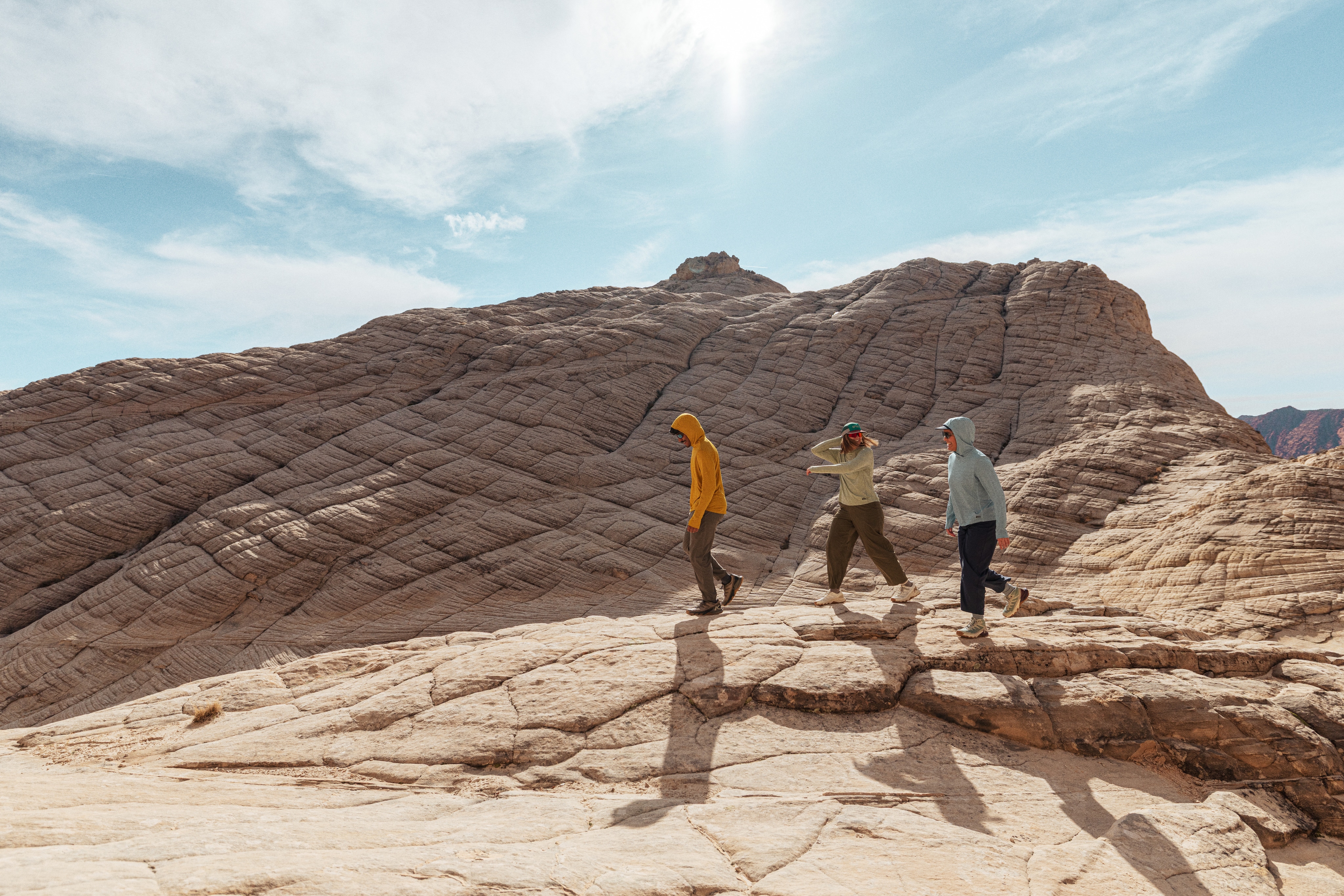 Three hikers cross a rock face