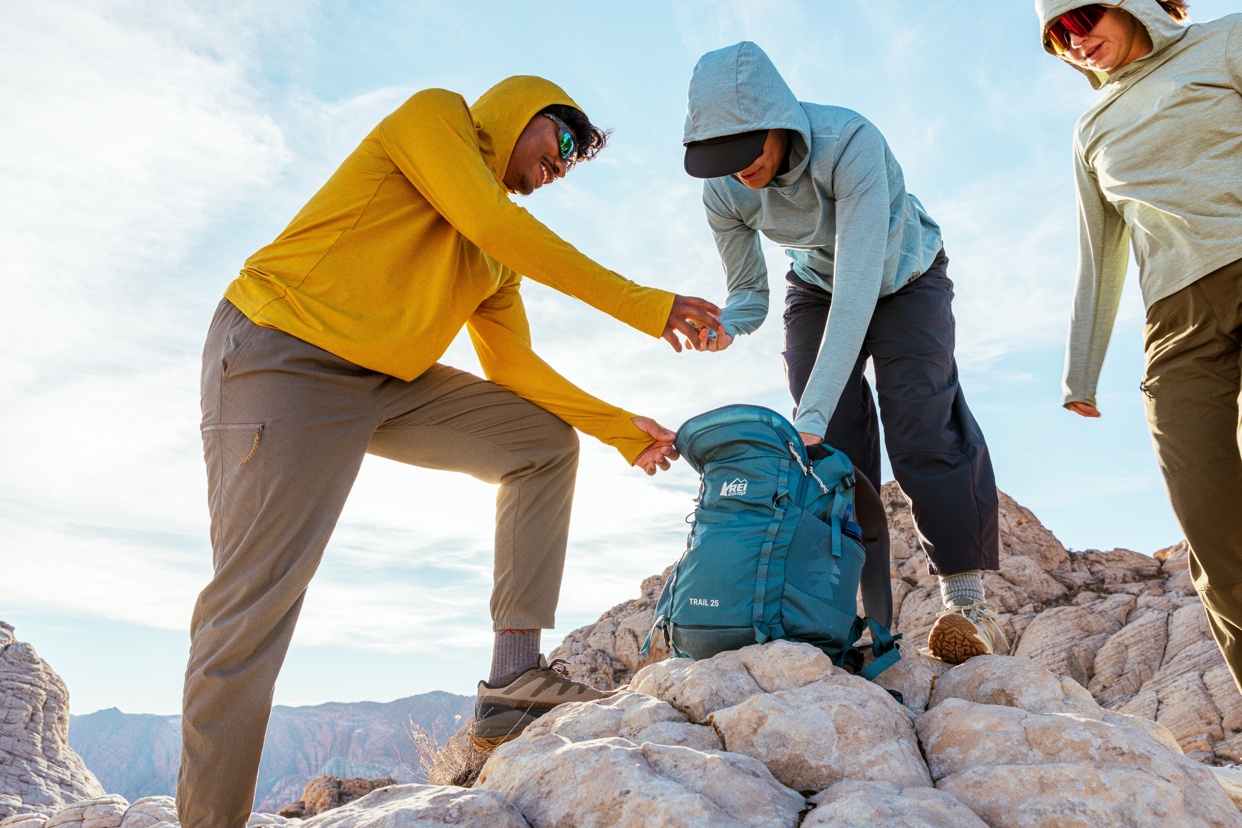 Three hikers pause on a rocky summit.
