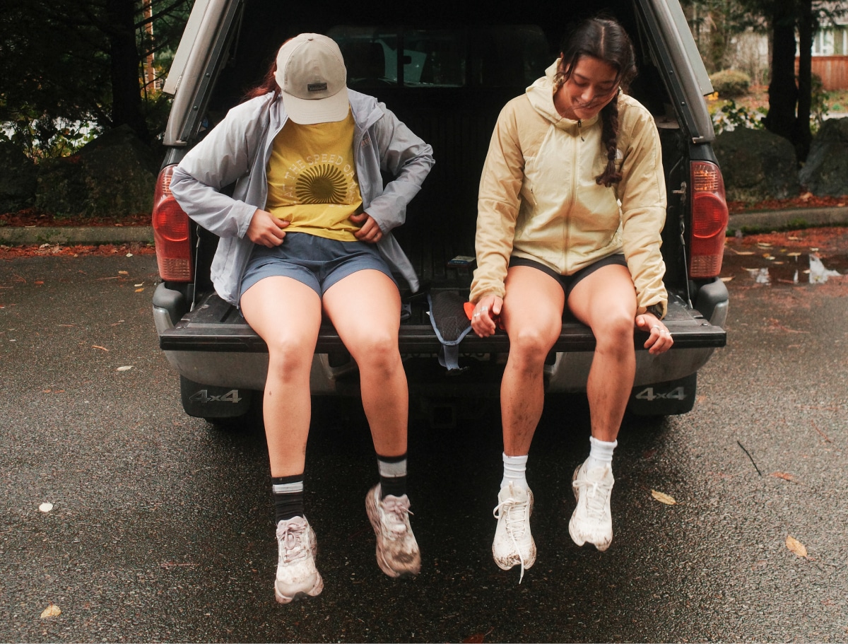 Two people take a break to sit down in the trunk of a car.