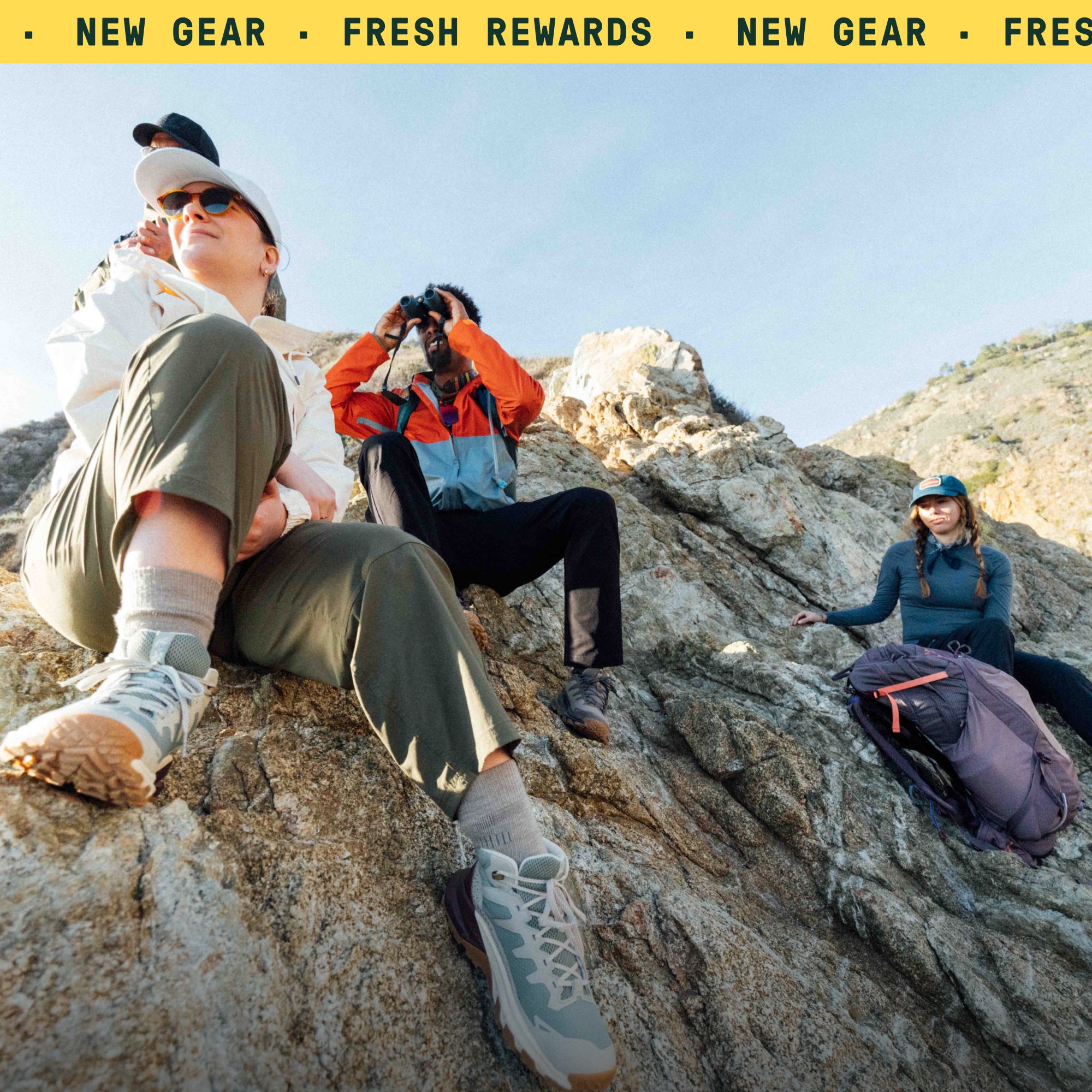 A group of people take a break from their hike to sit on a rock and take in the view.