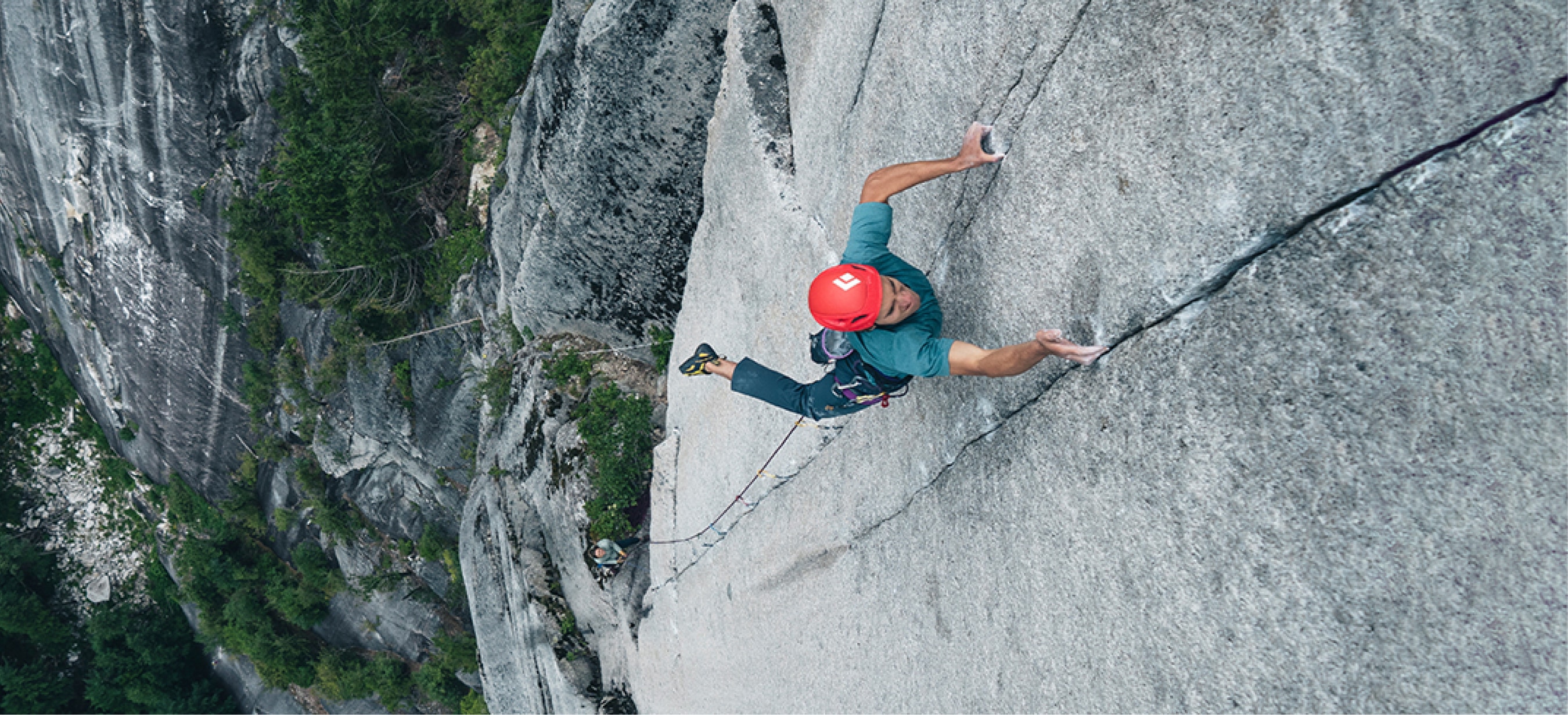 A person climbs up the face of a rock.
