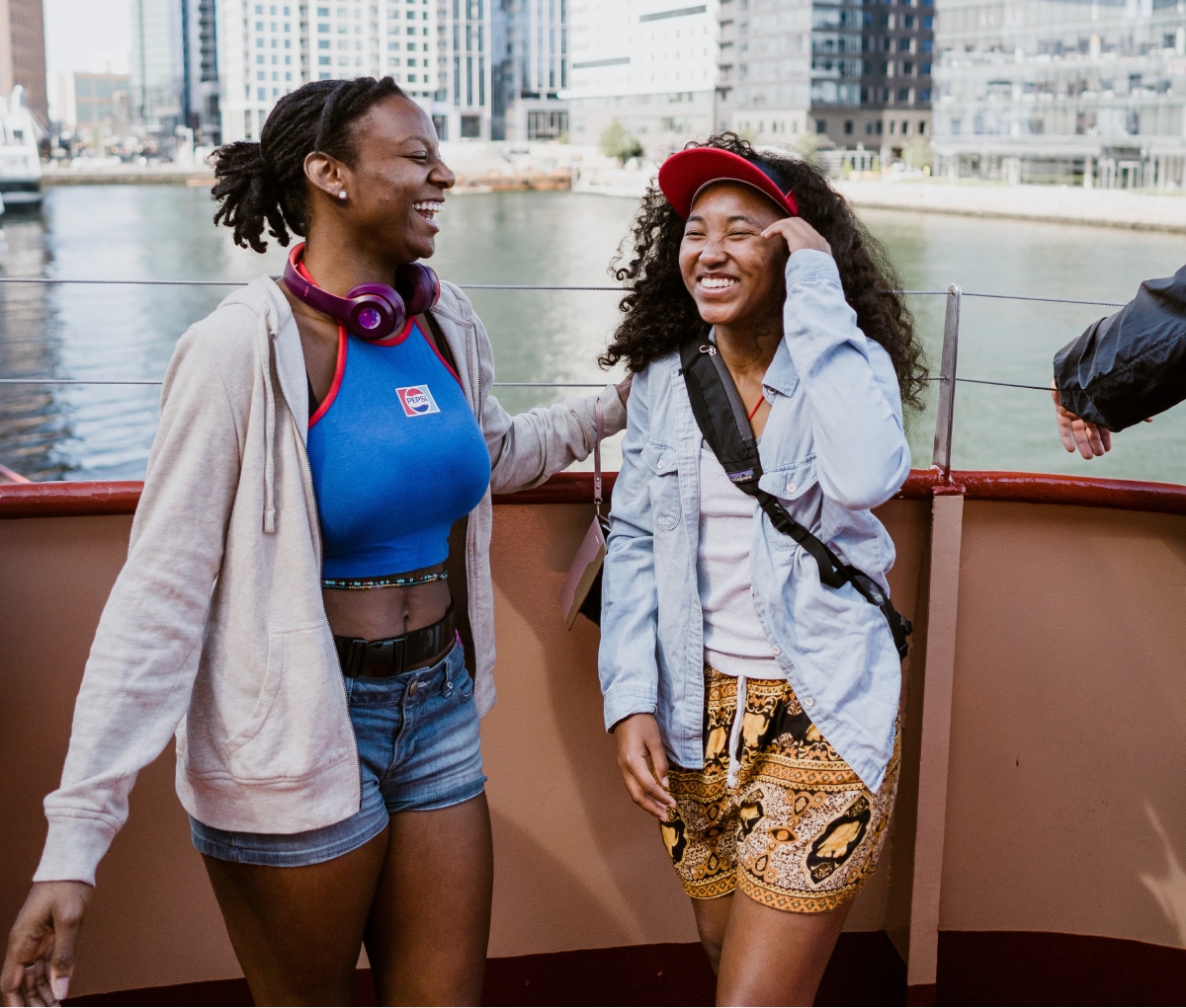 Two people laughing with a view of water and buildings in the background.
