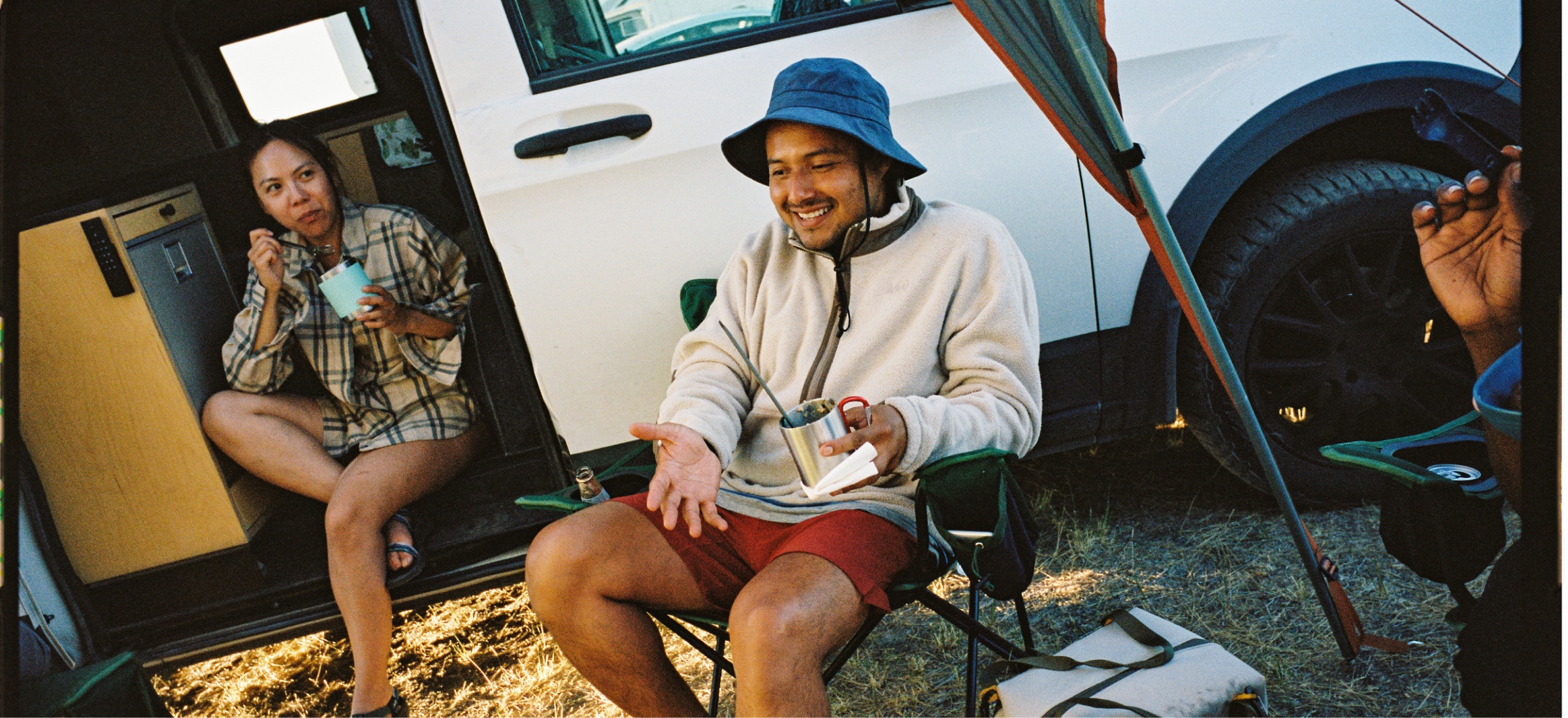 A group of people having conversation while eating at their campsite.
