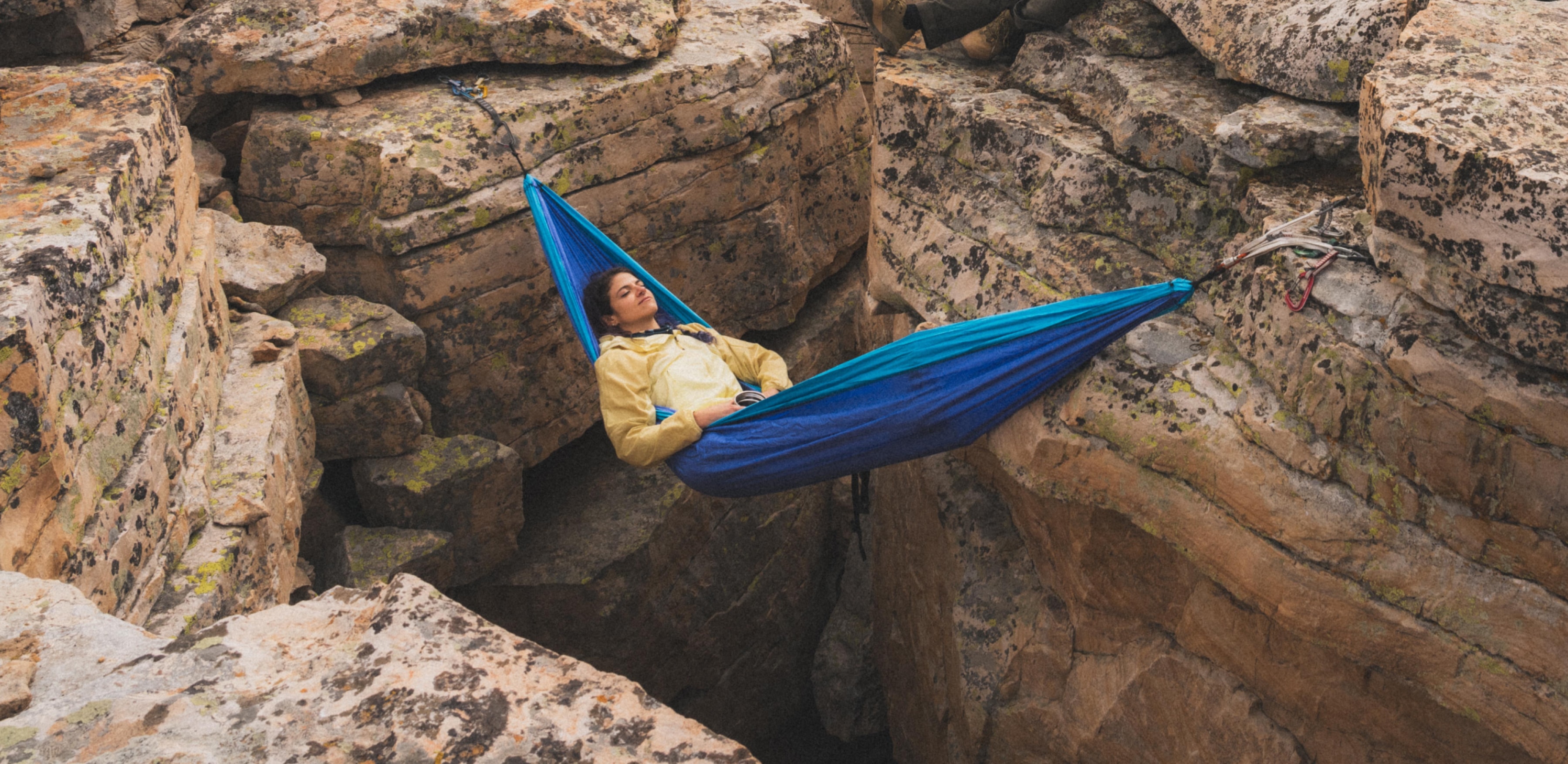 A person relaxes in a hammock surrounded by large rocks.