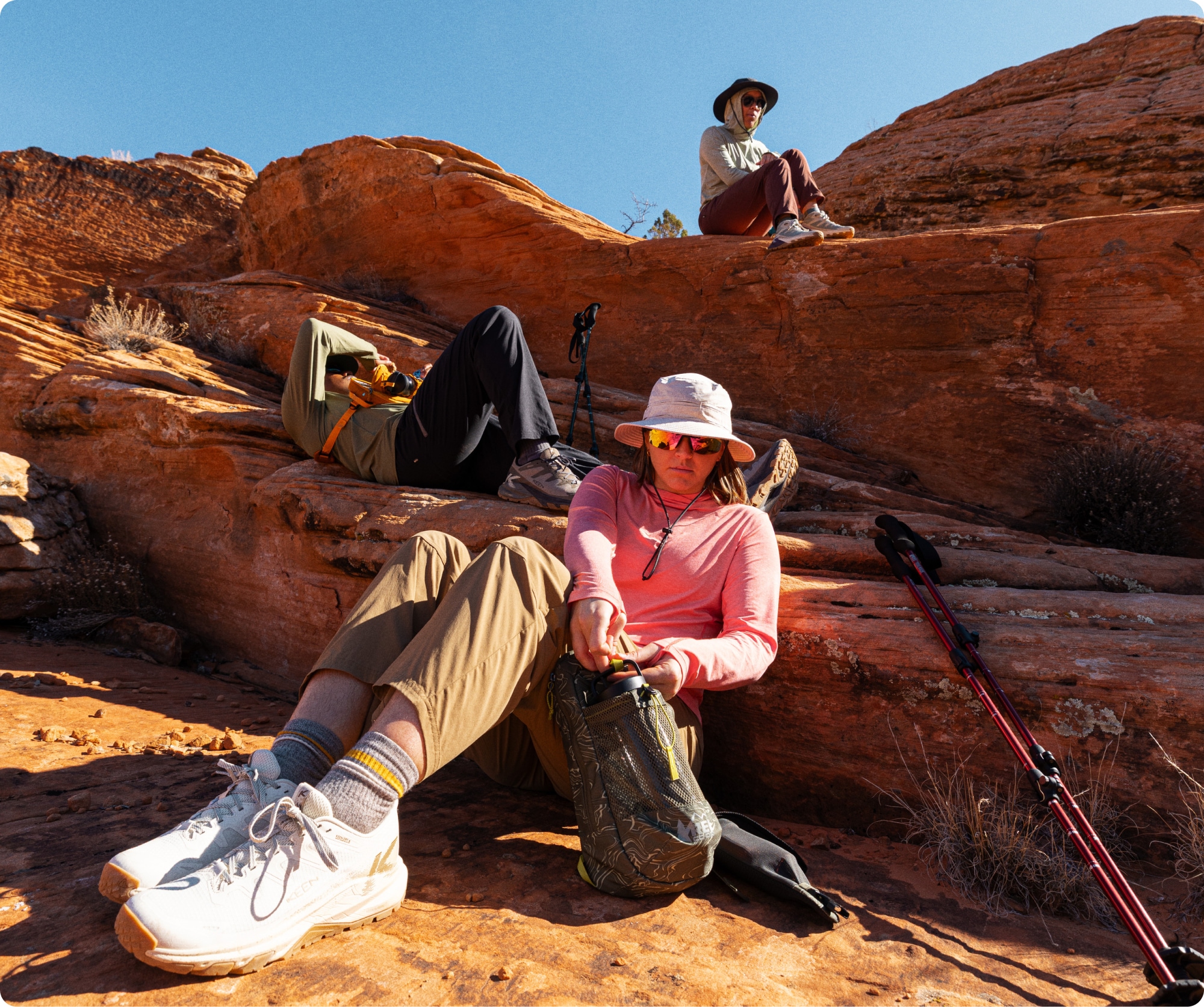 A group of people take a break from their hike to sit on top of large rocks.