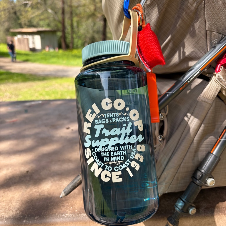 A Nalgene bottle is clipped to a carabiner on the back of a day pack