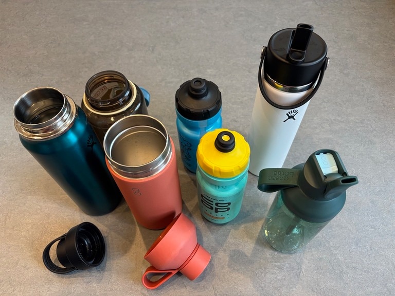 A collection of seven water bottles with different bottle openings and cap styles