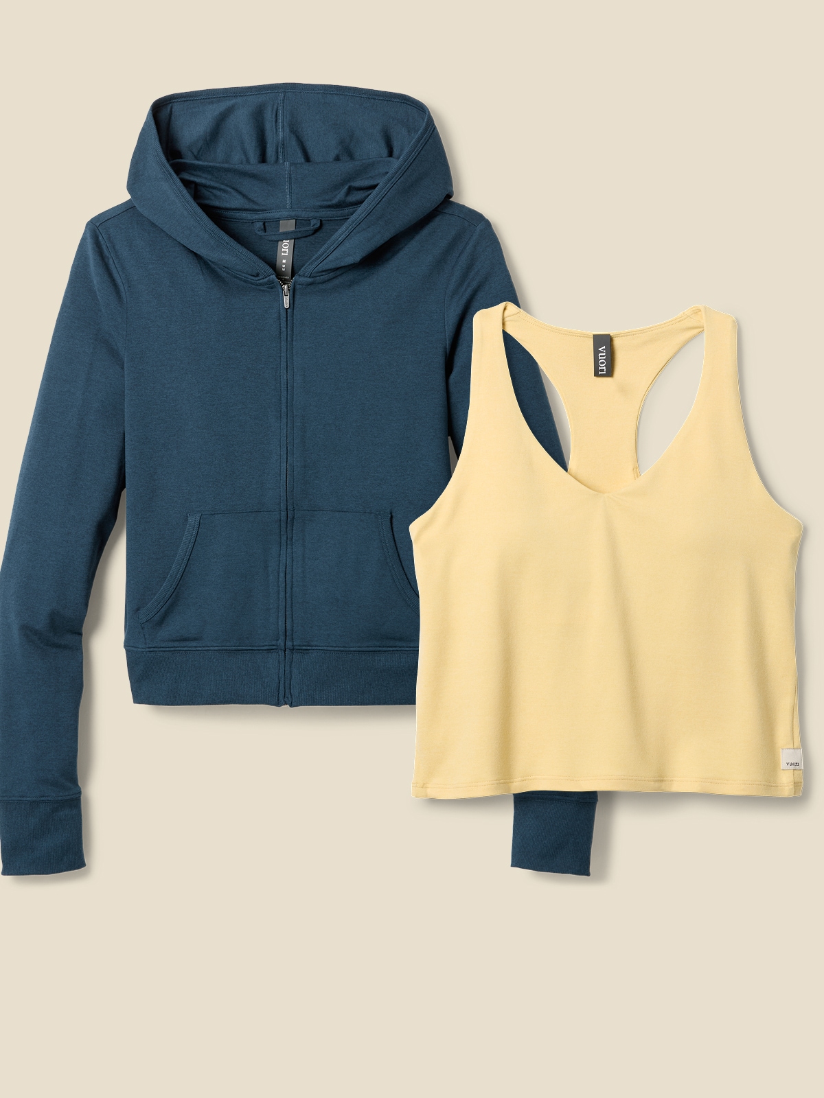 A women’s Vuori zip hoodie and cropped tank top on a light colored background.