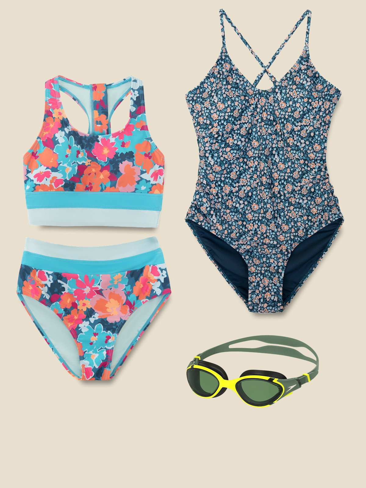 Two colorful swimsuits and a pair of goggles on a light colored background.