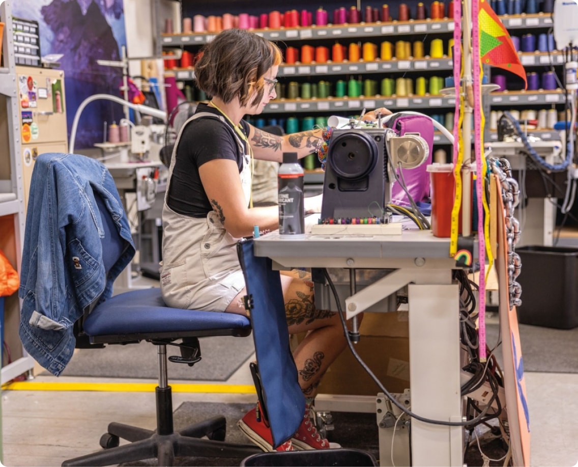 A person sits down at a sewing machine to repair an item.