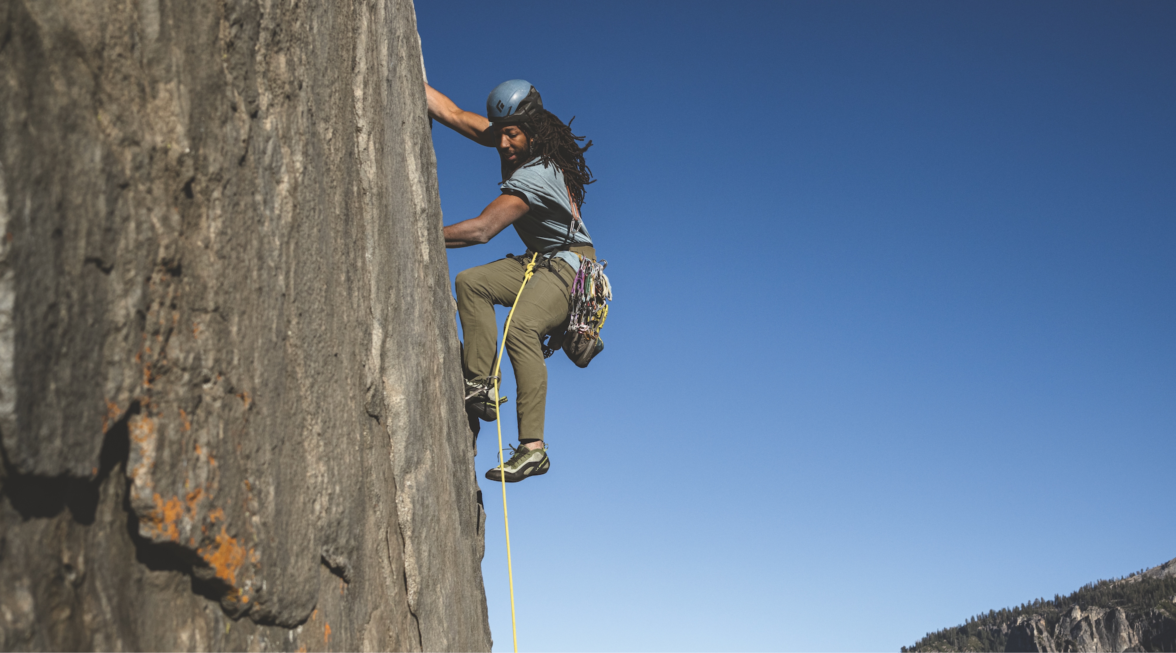 A person climbs up the side of a very steep rock.