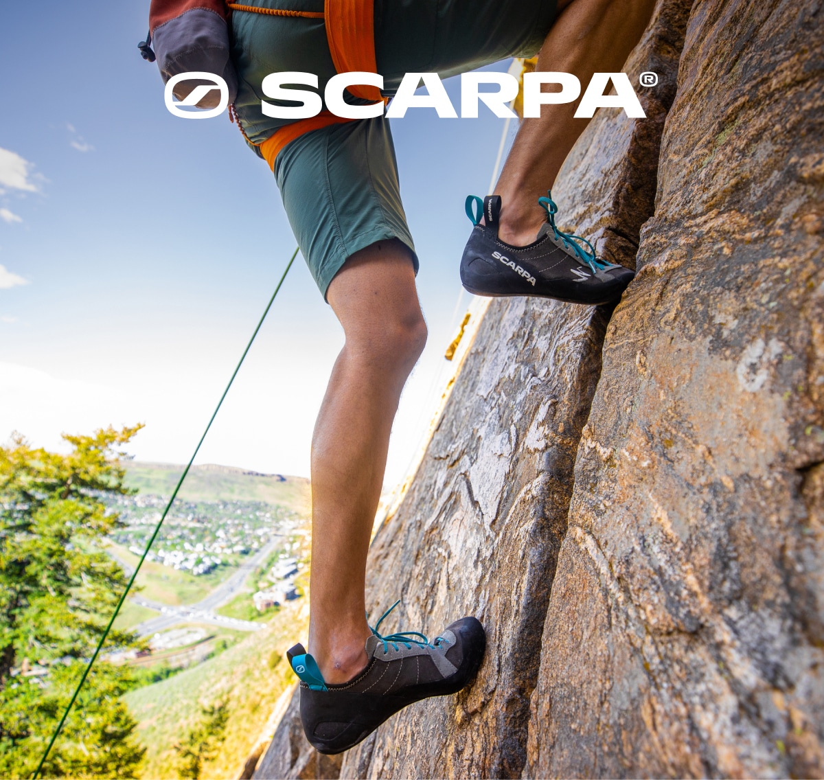 A person climbs up the side of a large rock in their Scarpa climbing shoes.