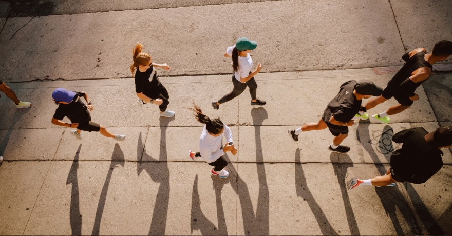 A group of people run along the sidewalk together.