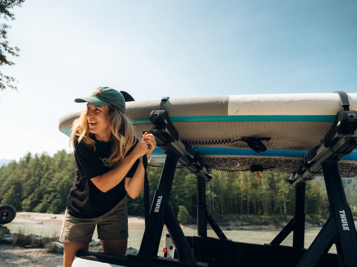 A person laughs while tightening the strap around their paddle board.