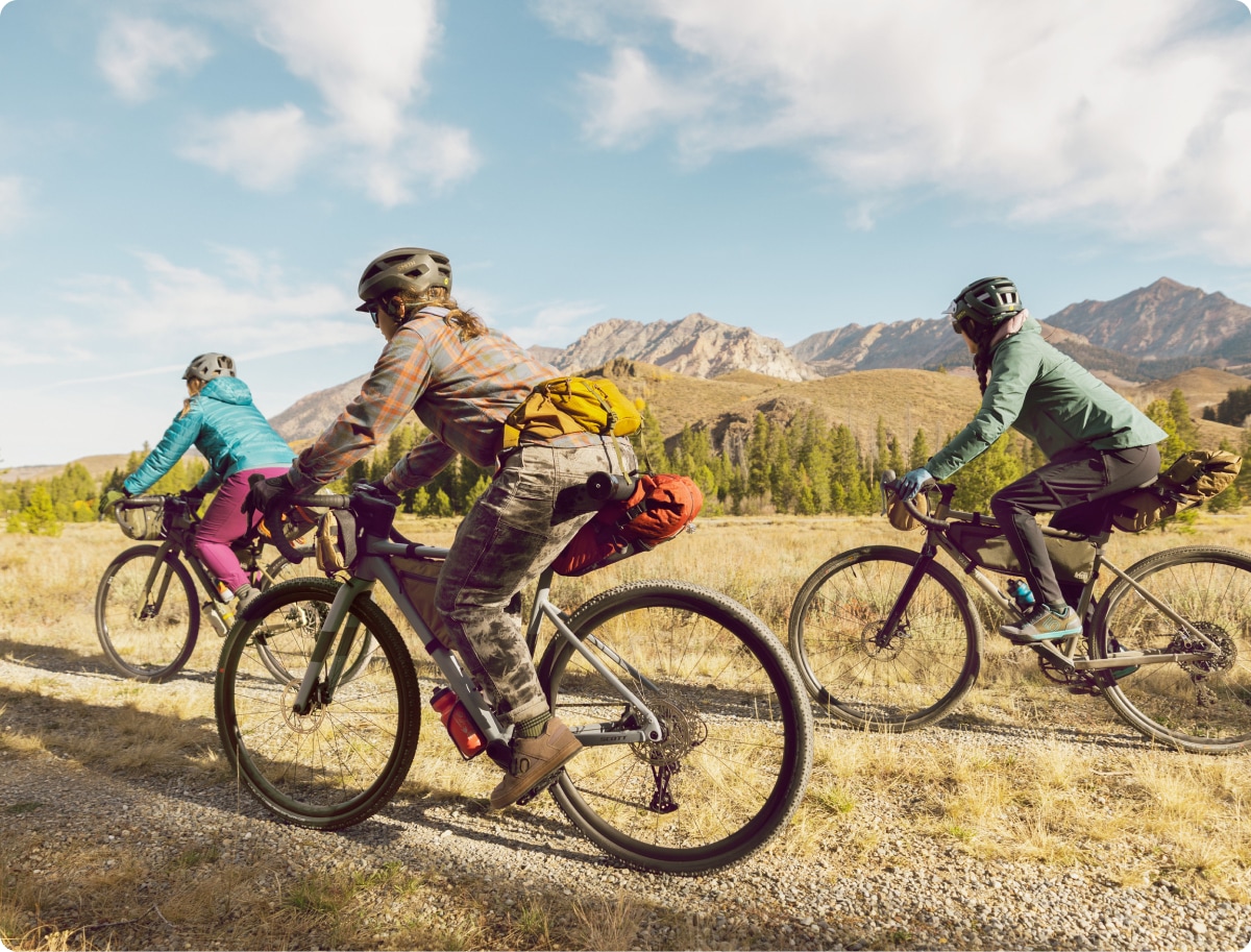 A group of three people riding gravel bikes on a sunny day.