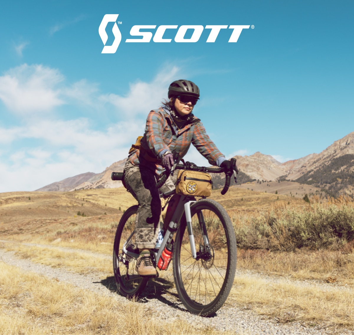 A person rides their Scott bike through a gravel path on a sunny day.