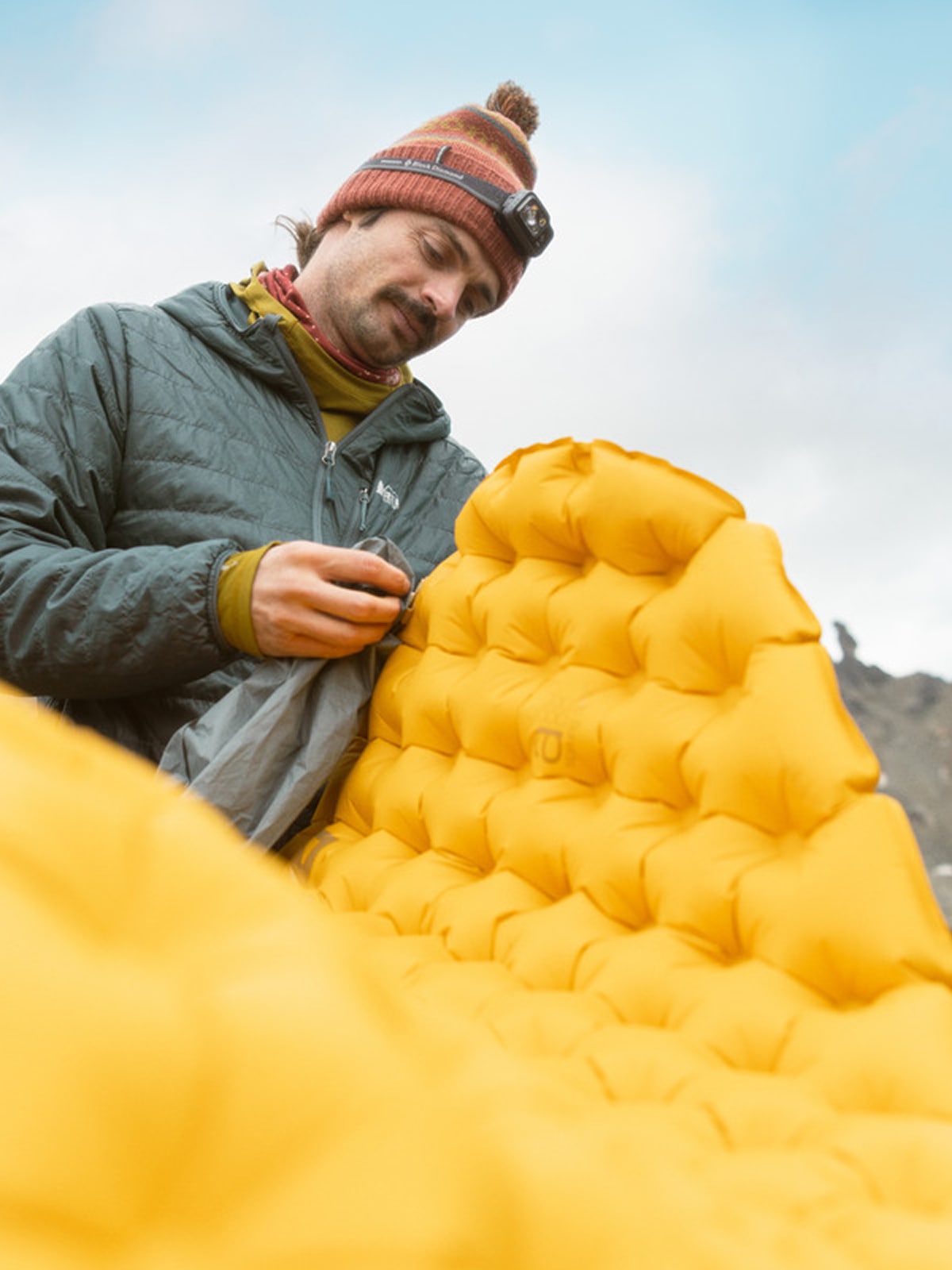 A person finishes inflating their sleeping pad.