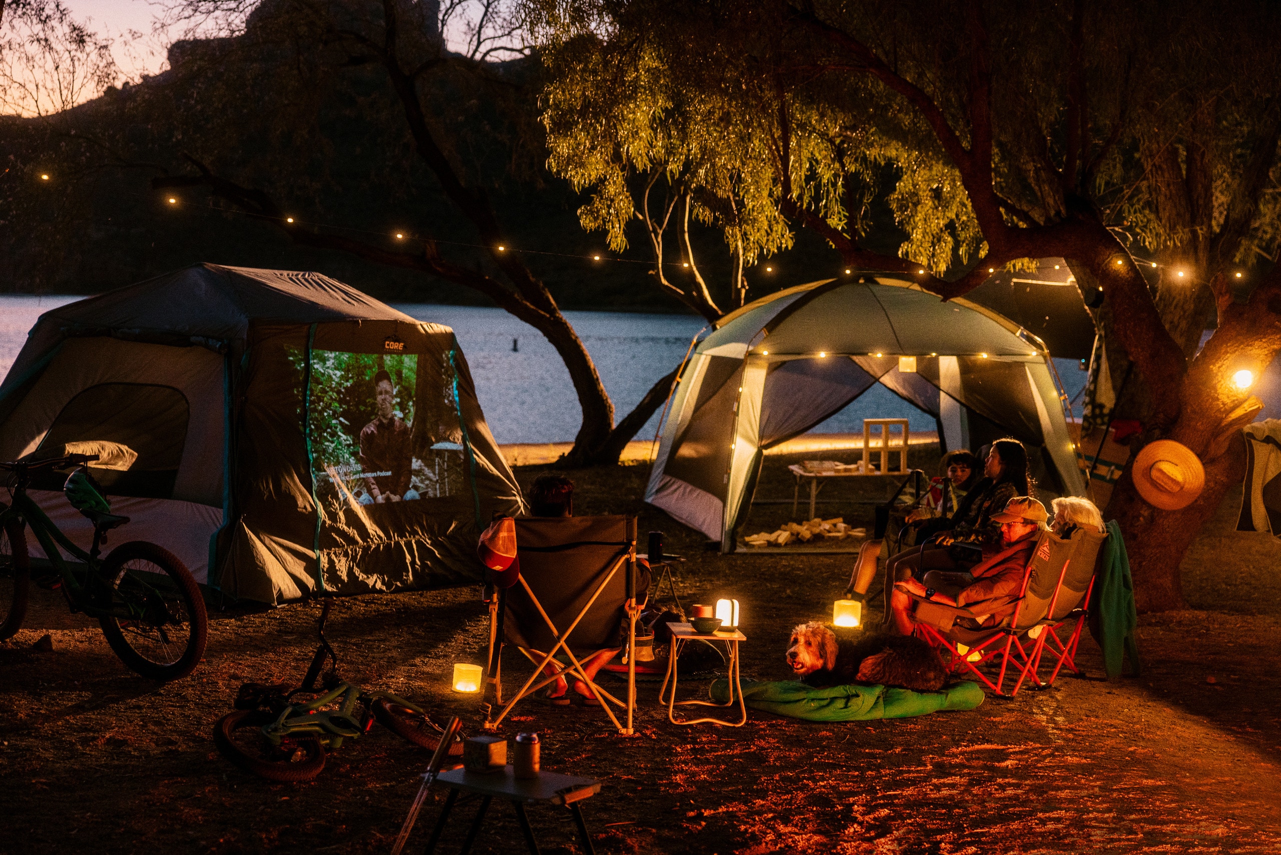 Picture of people gathered outside two tents at a campsite after dark