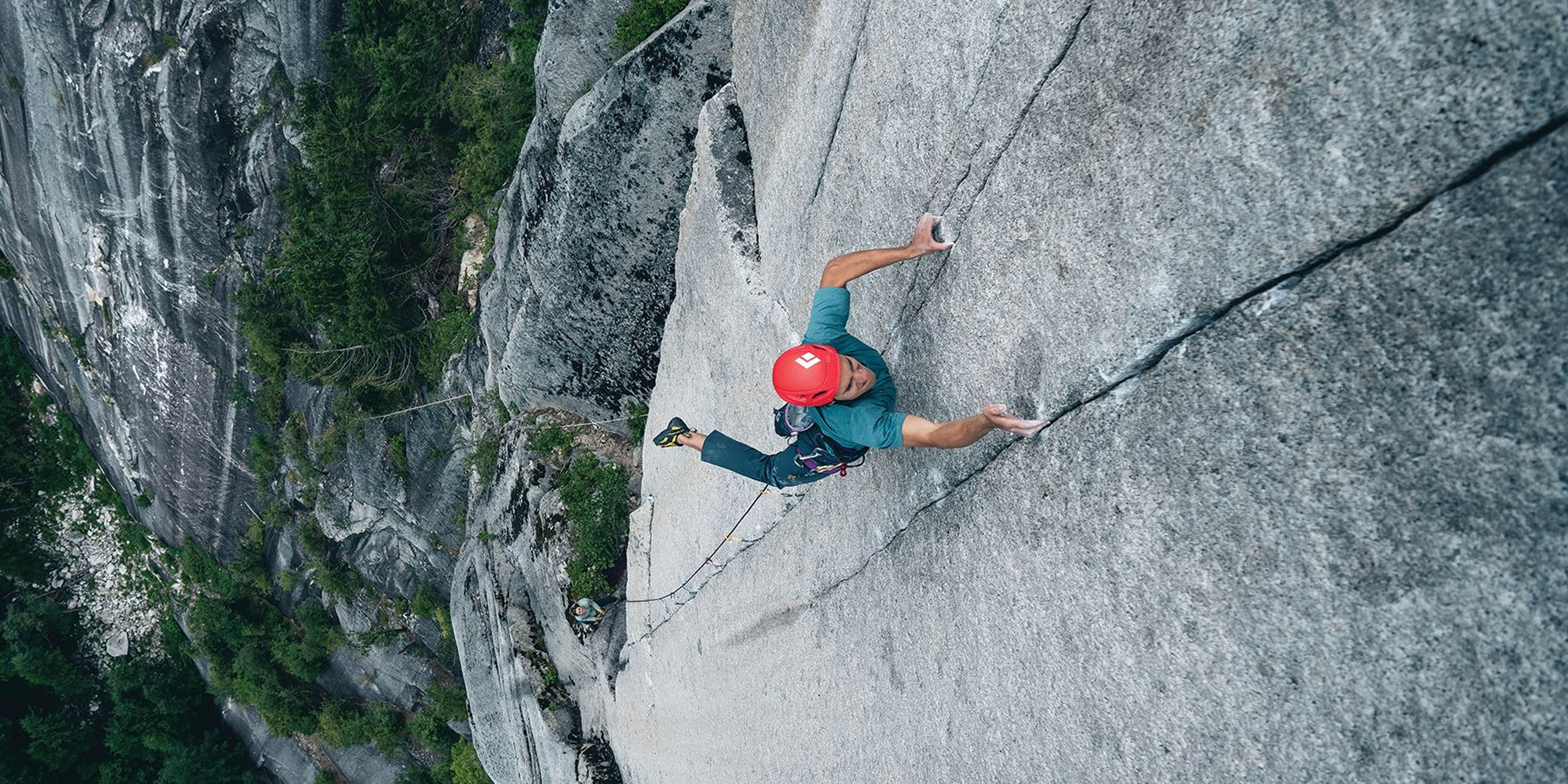 A person climbs up the face of a rock.