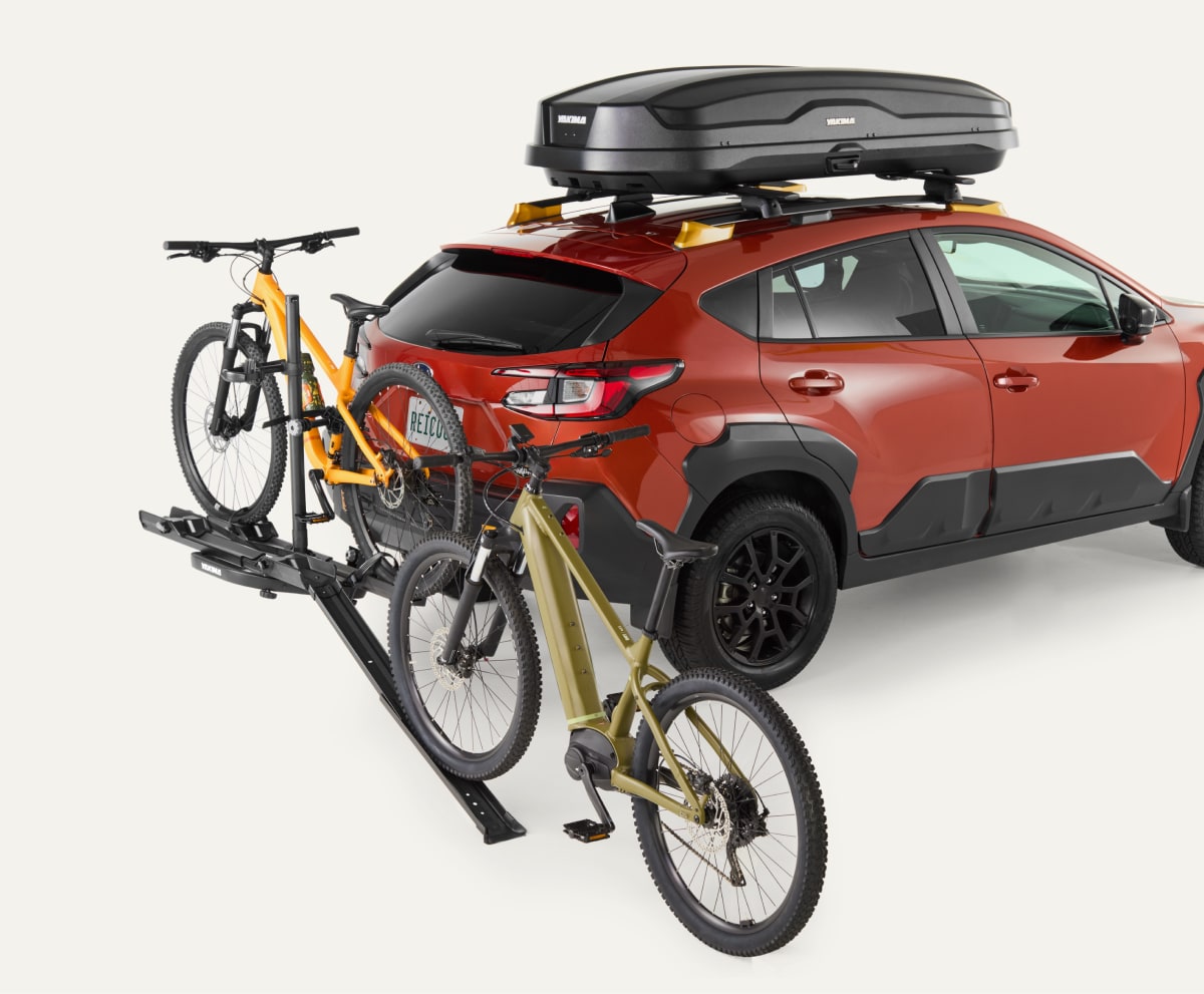 A car with a Yakima roof box and two bikes attached to a bike rack.