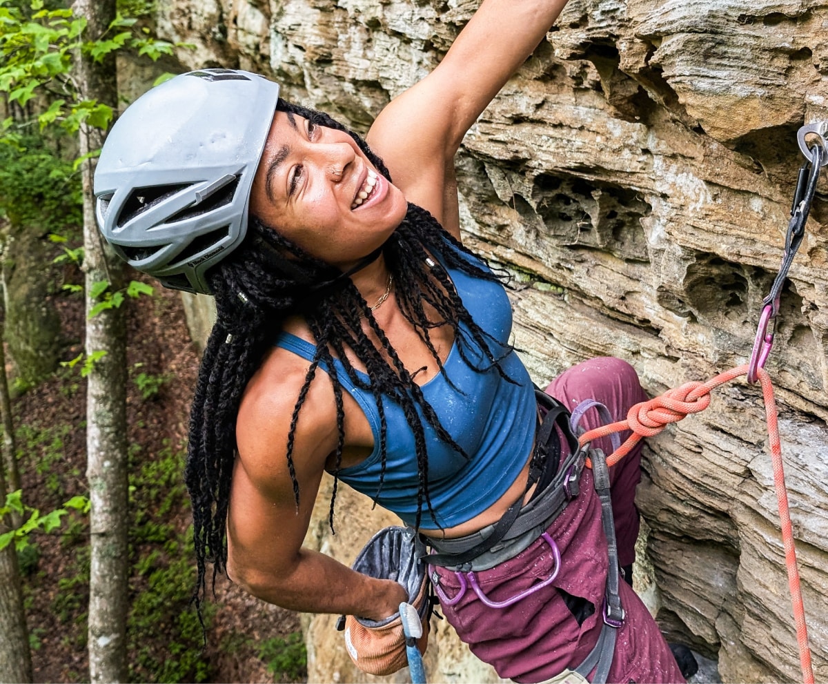 A person grabs more chalk while climbing up a rock face.