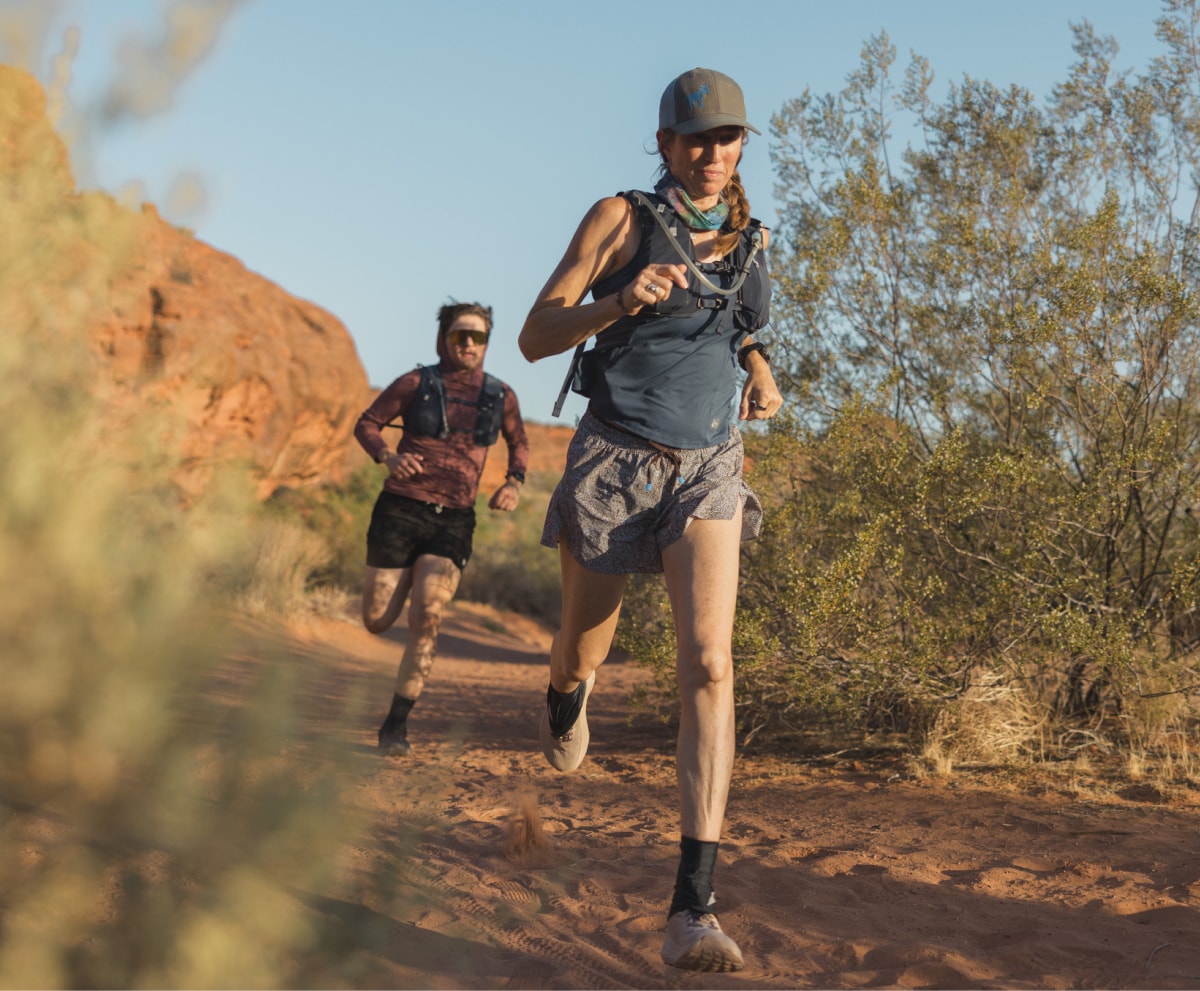 Two people run through a dirt trail.