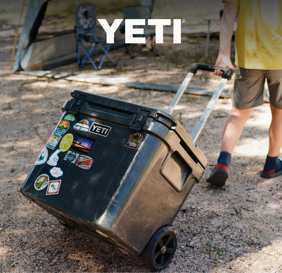 A person rolls a YETI Roadie Cooler to their campsite.