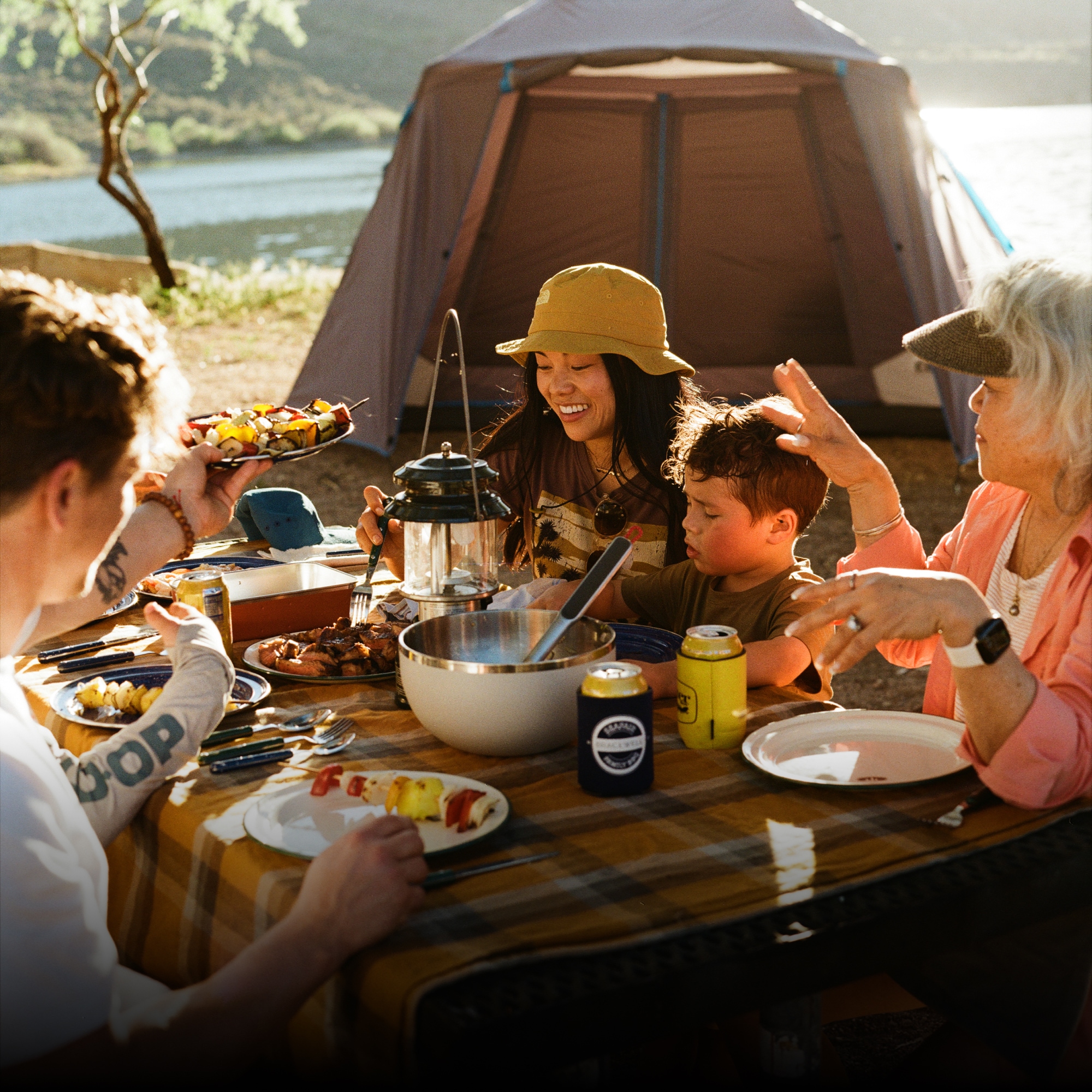 YETI & Coleman. A group of campers sit around a table to have food and drinks.