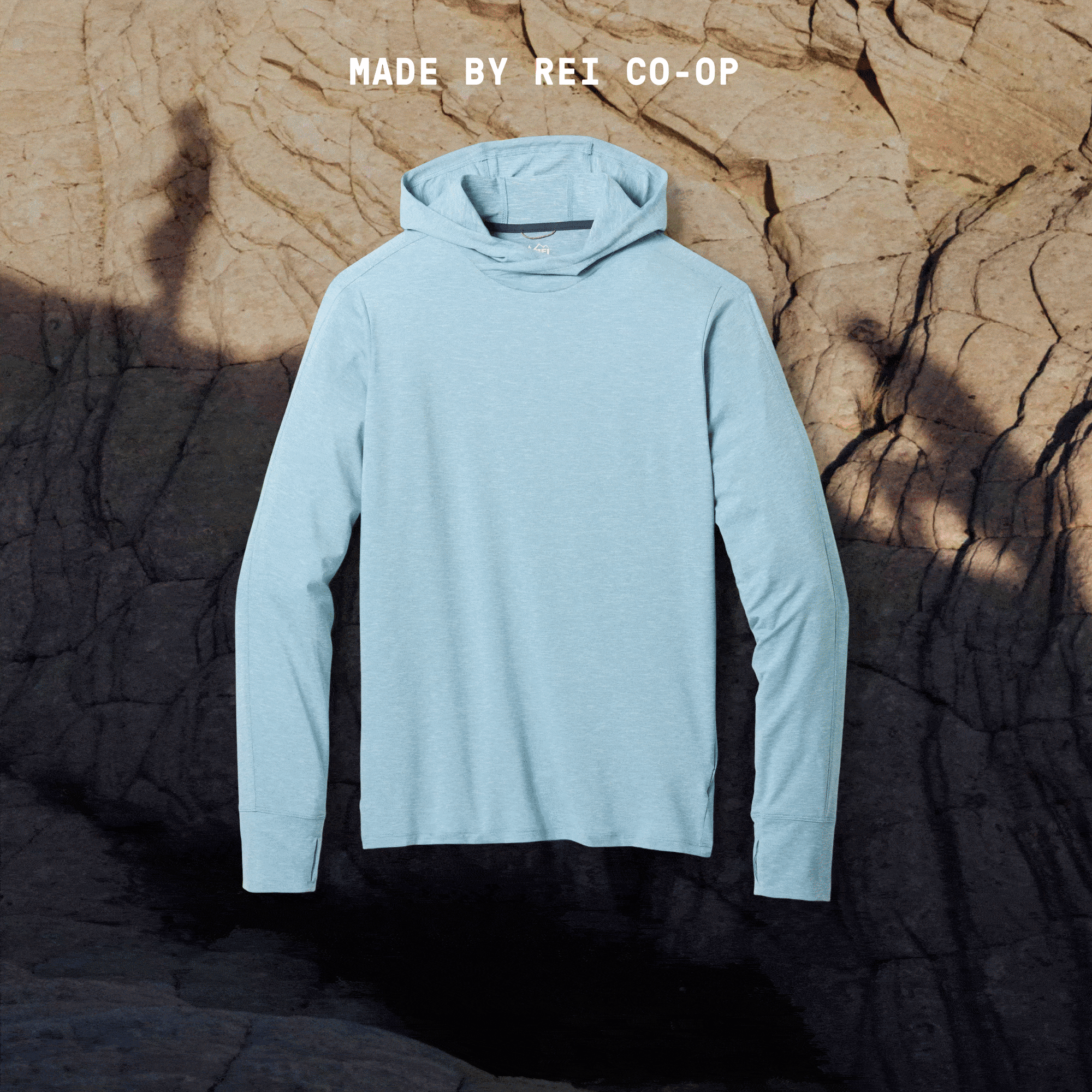 R E I Co-op. An animated GIF of a Sahara Shade Hoodie over a photo of a large rock with two shadows of people hiking.