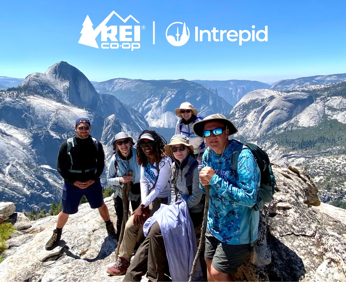 A group of people pose together for a photo in Yosemite with large mountains in the background.