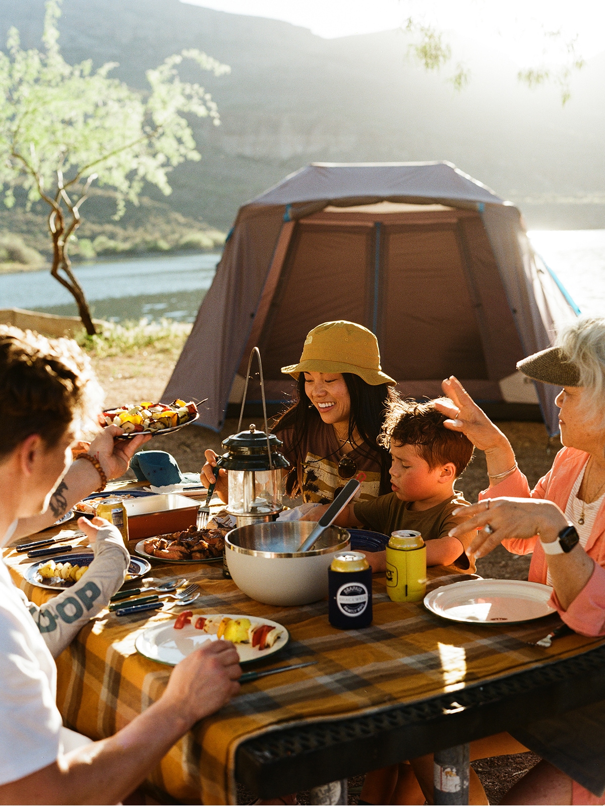 A group of campers sit around a table to enjoy a meal together.