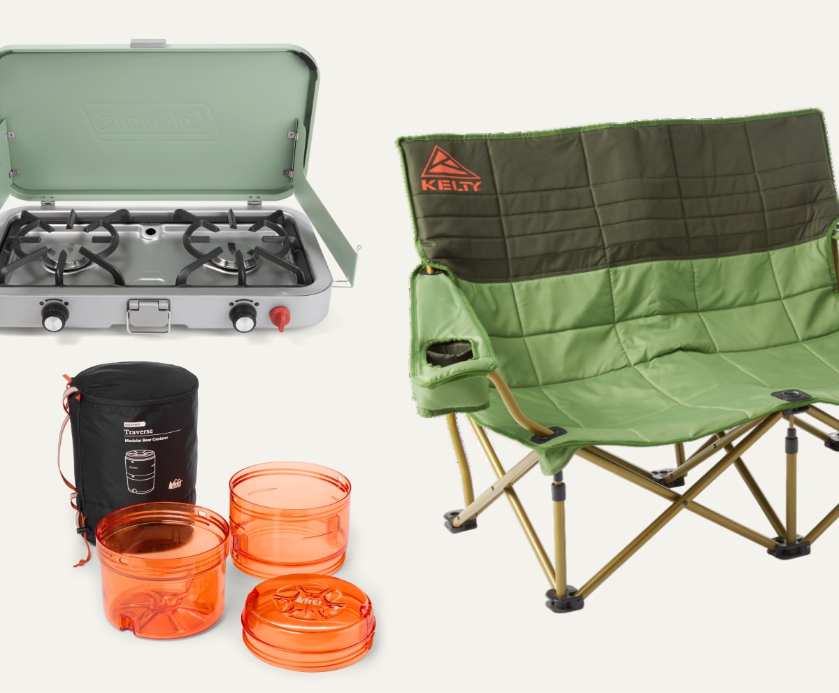 A Coleman portable stove, a KELTY camp chair, and an R E I Co-op brand Bear Canister on a light colored background.
