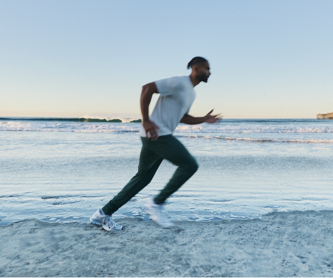 A person runs along the beach in their Vuori clothing.