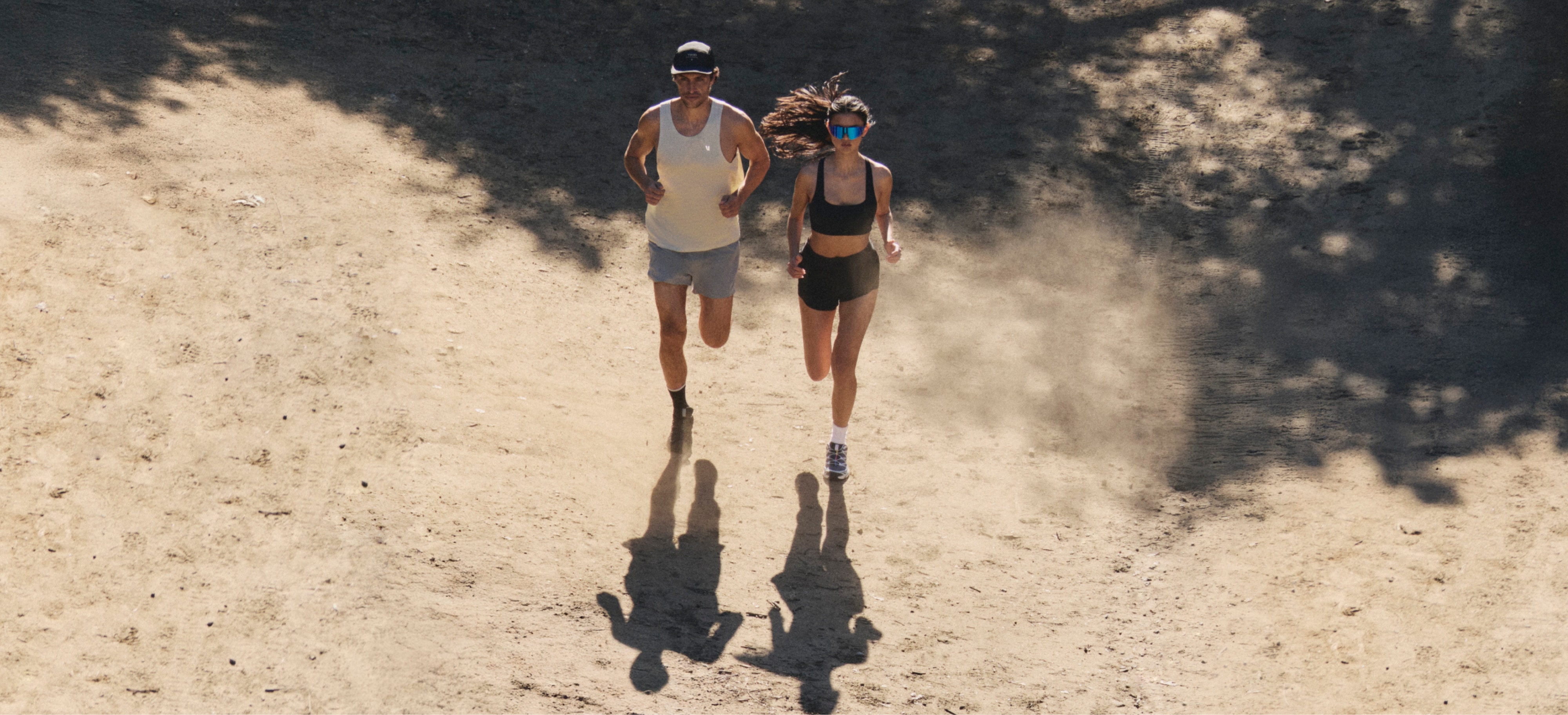 Two people run through a dirt trail together in their Vuori clothing.