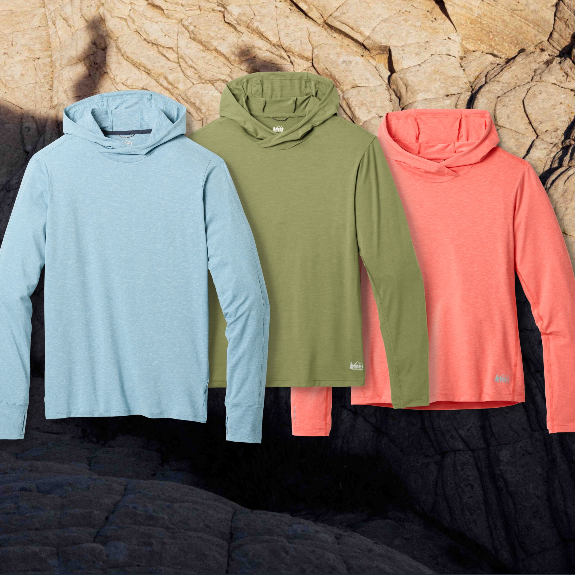 Three Sahara Shade Hoodies over a photo of a large rock with two shadows of people hiking.