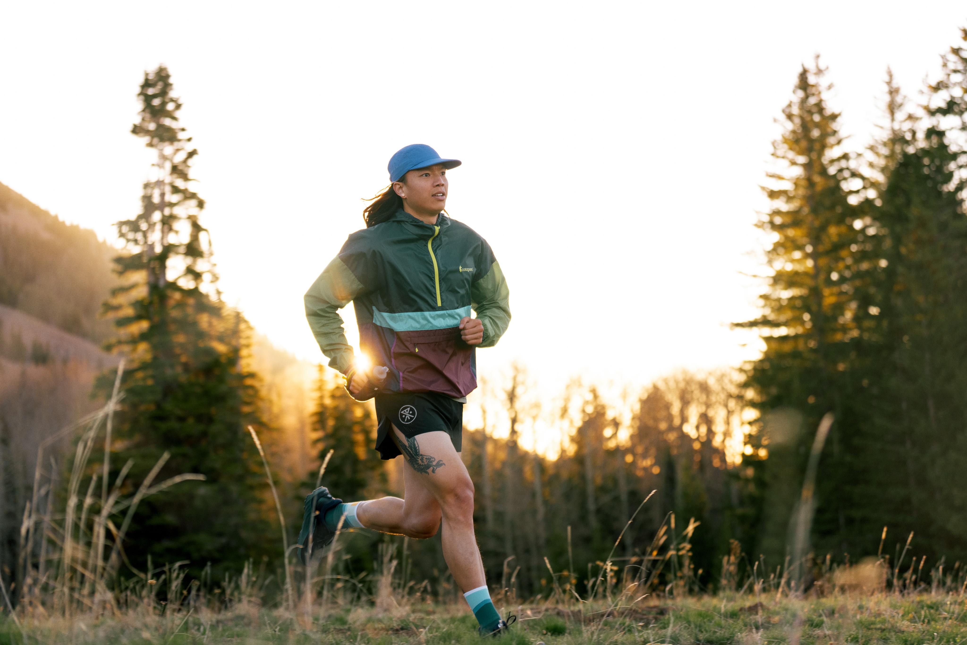 A person runs through a trail surrounded by grass and trees.