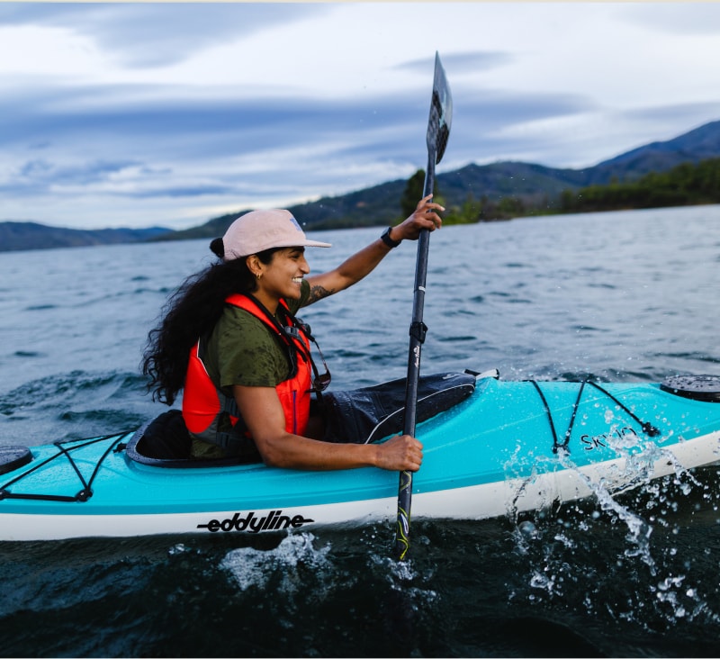 A person smiles while kayaking.