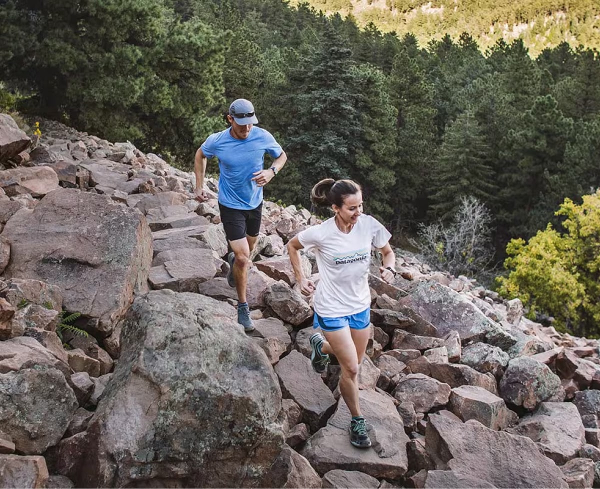 Two people run down a rocky path.