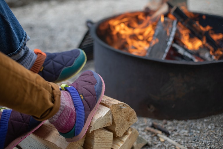 Picture of two campers' slippered feet near a campfire