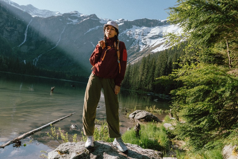 A hikers stands on rocks near an alpine lake