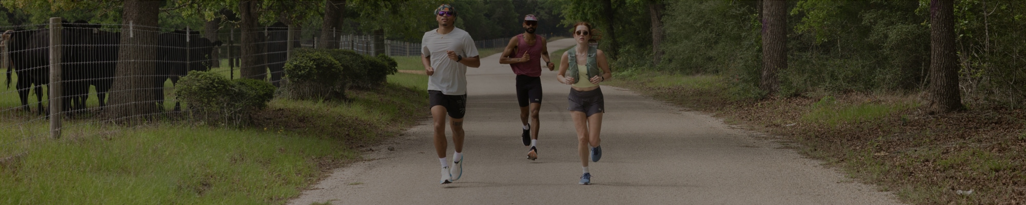 Three people running together on a paved road.