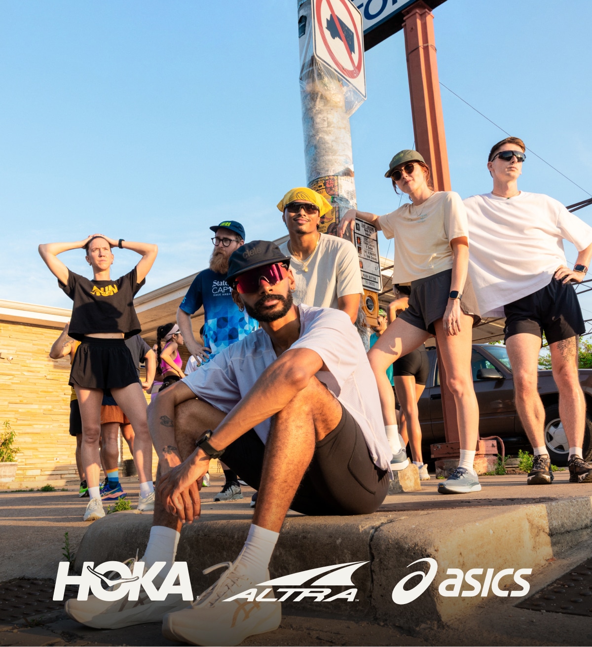 HOKA, Altra, and ASICS. A a person sitting down with a group of runners standing in the background.