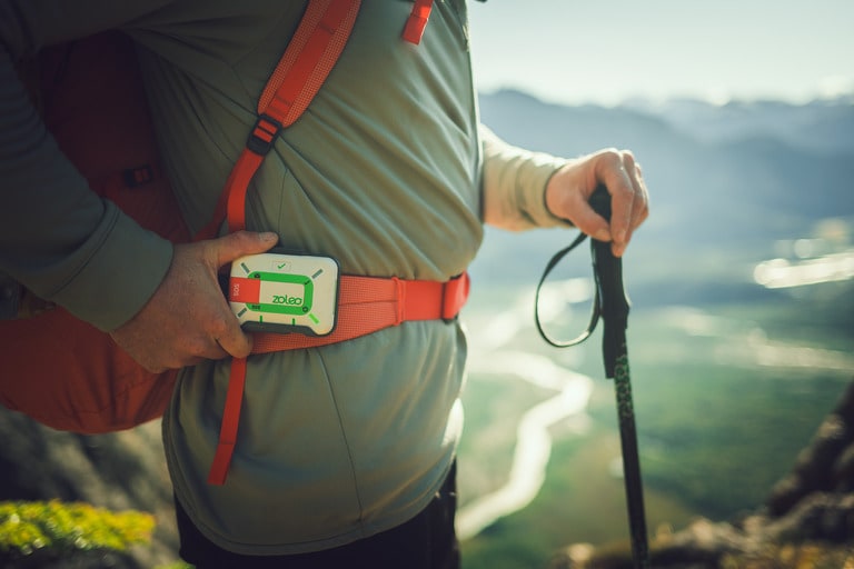 A hiker has a ZOLEO satellite messengers attached to a backpack