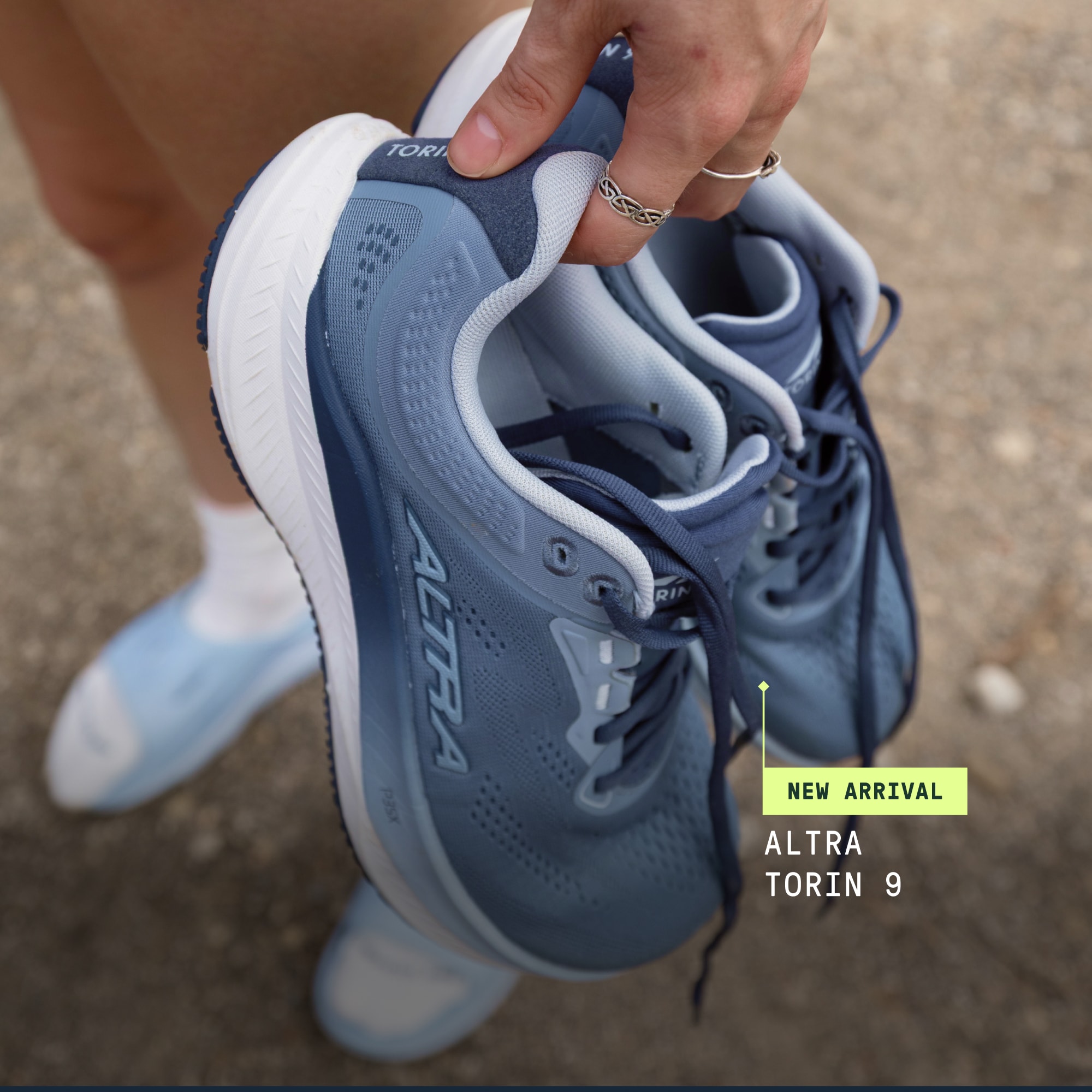 A person carrying their Altra Torin 9 running shoes.