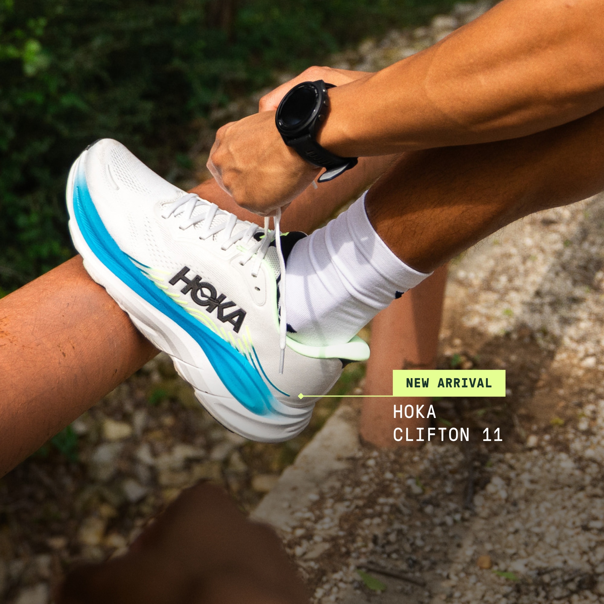 A runner stops to tie the laces on their HOKA Clifton 11 shoe. 