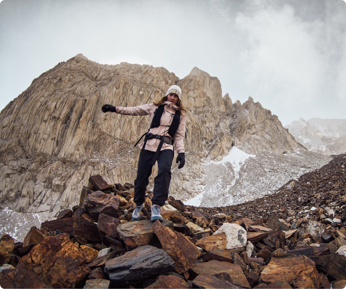 A person bundled up in Arc’teryx gear hikes down a rocky path.