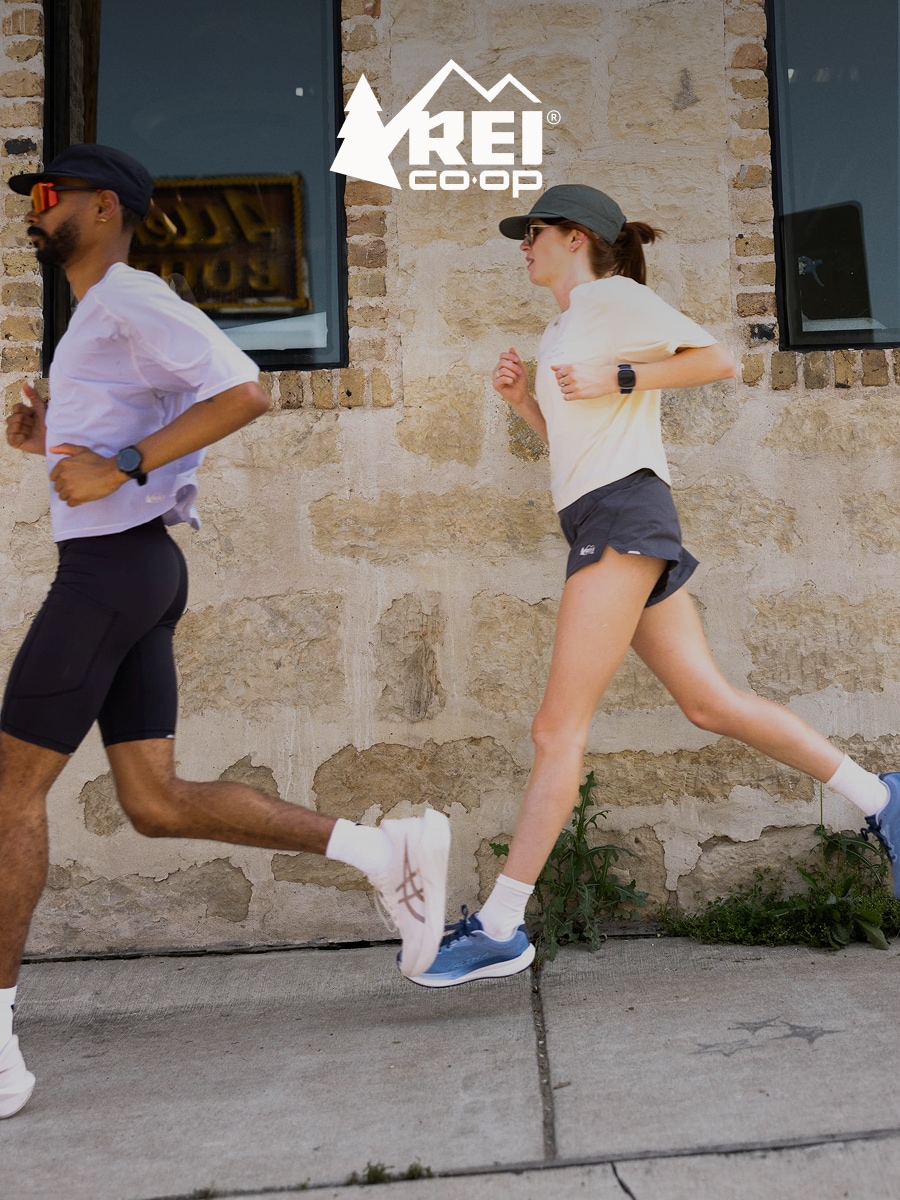 Two people run together on a paved sidewalk.