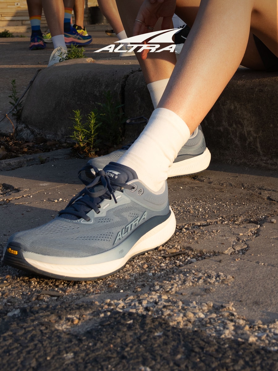 A person sitting down in their Altra running shoes.